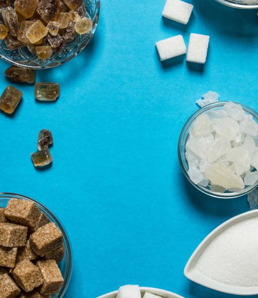 Different types of brown and white sugar. On a blue table.